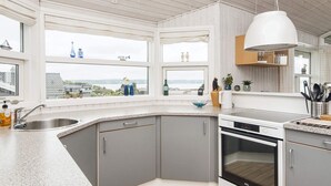 Une cuisine moderne dotée d’une grande fenêtre, d’un four encastré et d’un plan de travail en granit.