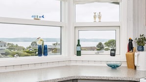 Une cuisine donnant sur un lac, une bouteille de vin et un bol bleu posé sur le comptoir.