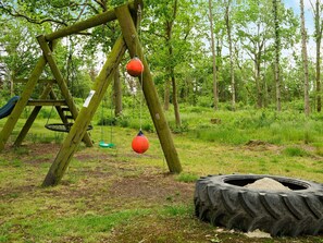 A playground with a swing set and tire swings in a wooded area. - 4 Person Holiday Home in Skaerbaek (Skaerbaek)
