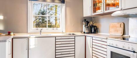 A modern kitchen with a window, built-in cabinets, a stove, and a coffee maker.
