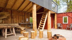 A rustic wooden building with a wooden table and benches, a ladder, and a pile of bricks. - 4 Person Holiday Home in Skaerbaek (Skaerbaek)