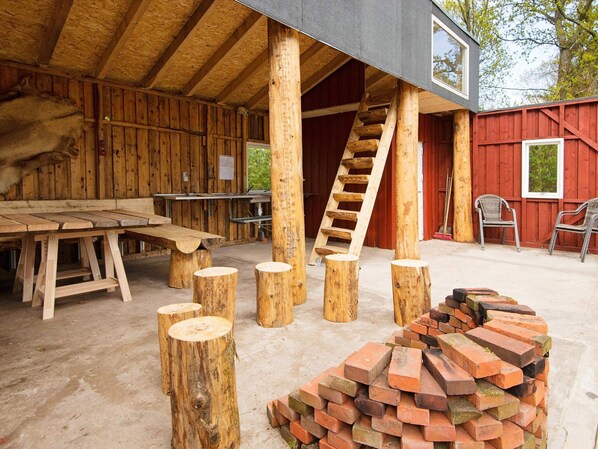 A rustic wooden building with a wooden table, a ladder, and a pile of bricks.