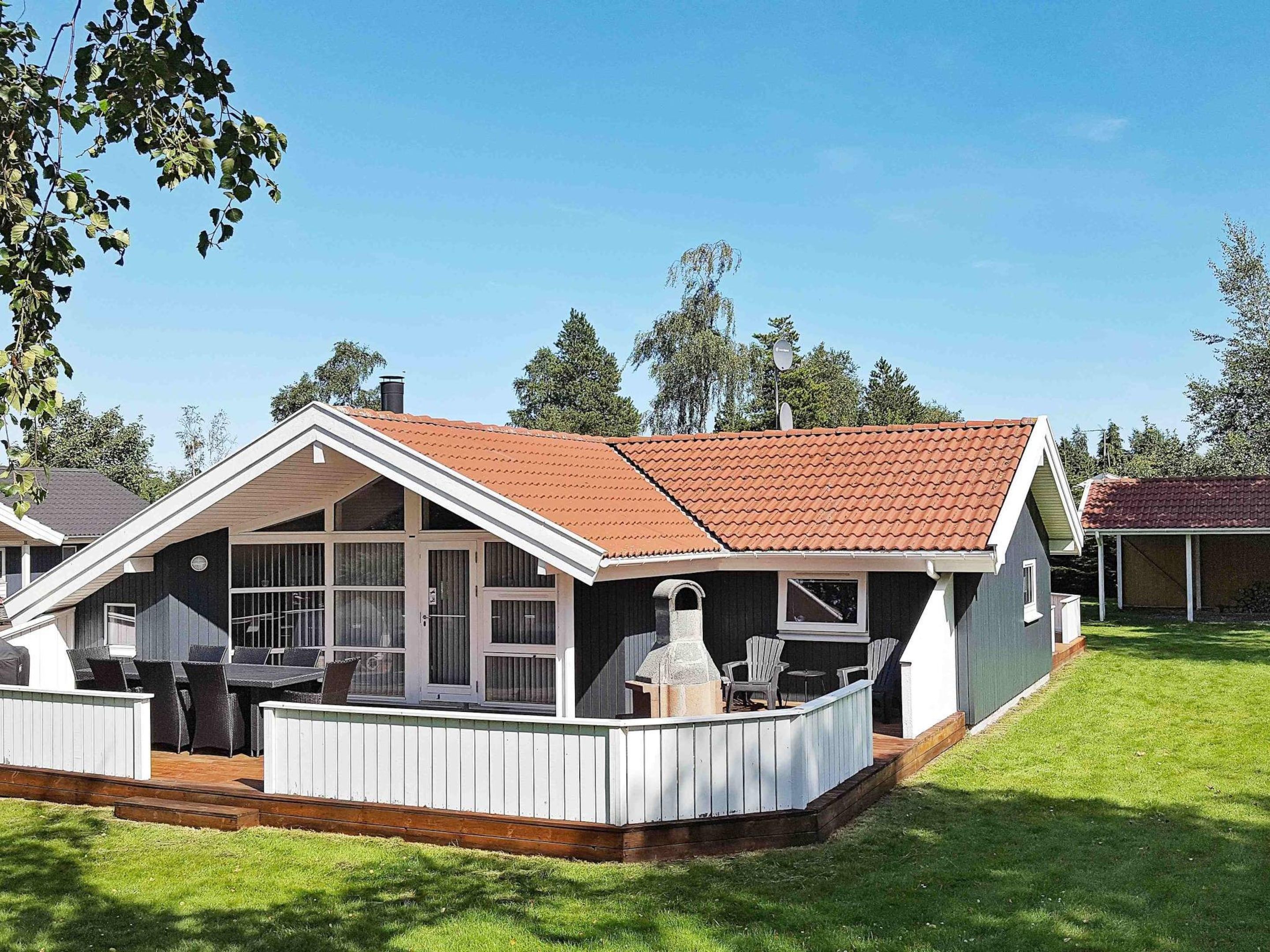 A two-story house with a covered patio, a chimney, and a satellite dish.