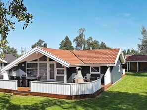 A two-story house with a covered patio, a chimney, and a satellite dish. - 5 Star Holiday Home in Vaeggerlose (Vaeggerlose)