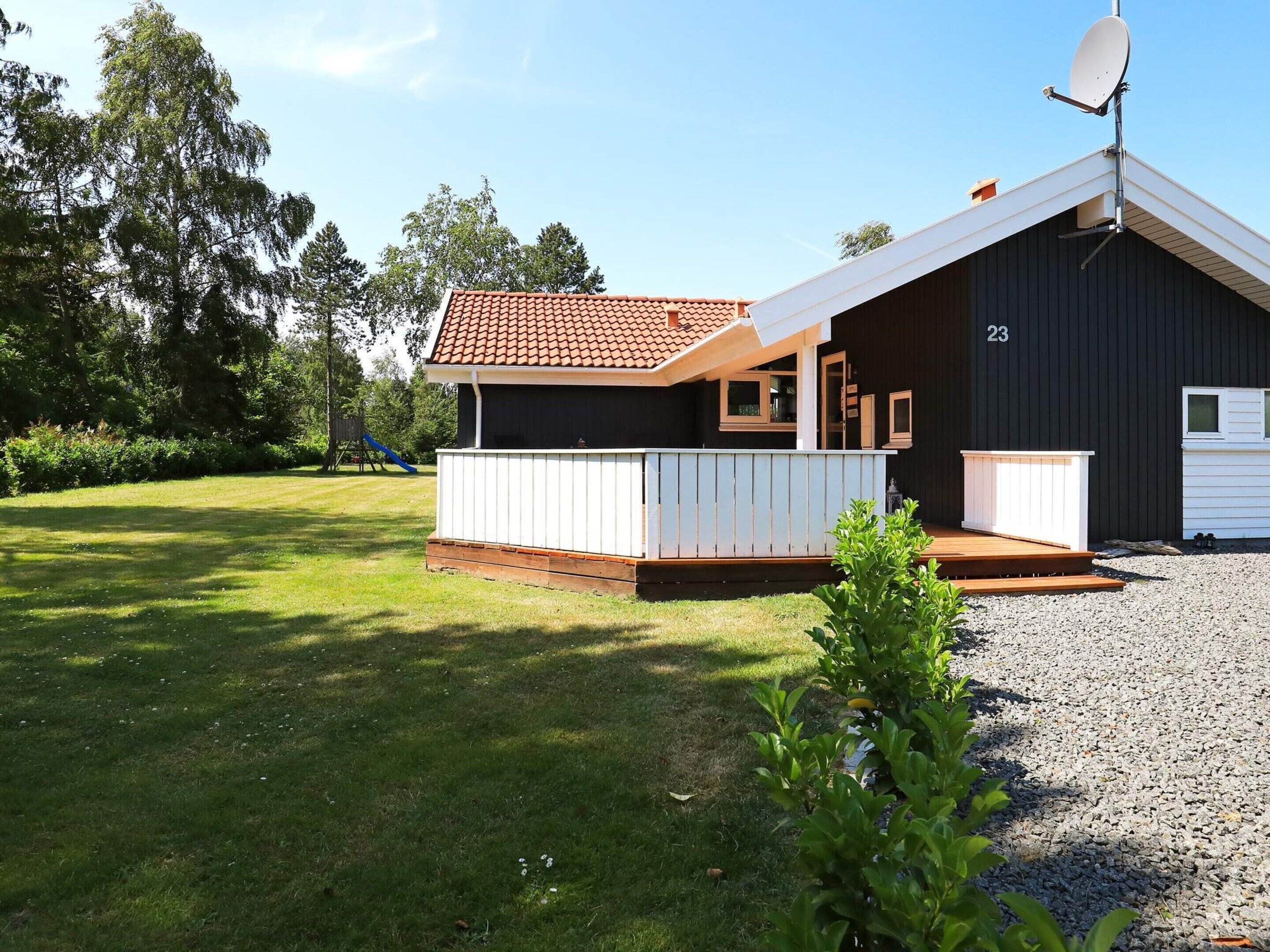 A single-story building with a dark exterior, a white porch, and a satellite dish.