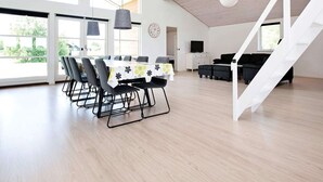 A spacious room with a dining table, chairs, a sofa, and a staircase. - 10 Person Holiday Home in Rodby-by Traum (Rodby)