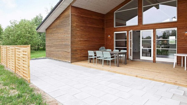 A modern building with a wooden exterior, large glass windows, and a patio area with outdoor seating. - 10 Person Holiday Home in Rodby-by Traum (Rodby)
