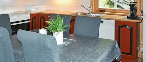 A compact kitchen with a dining table, chairs, a coffee machine, and a window with a view of the outdoors.