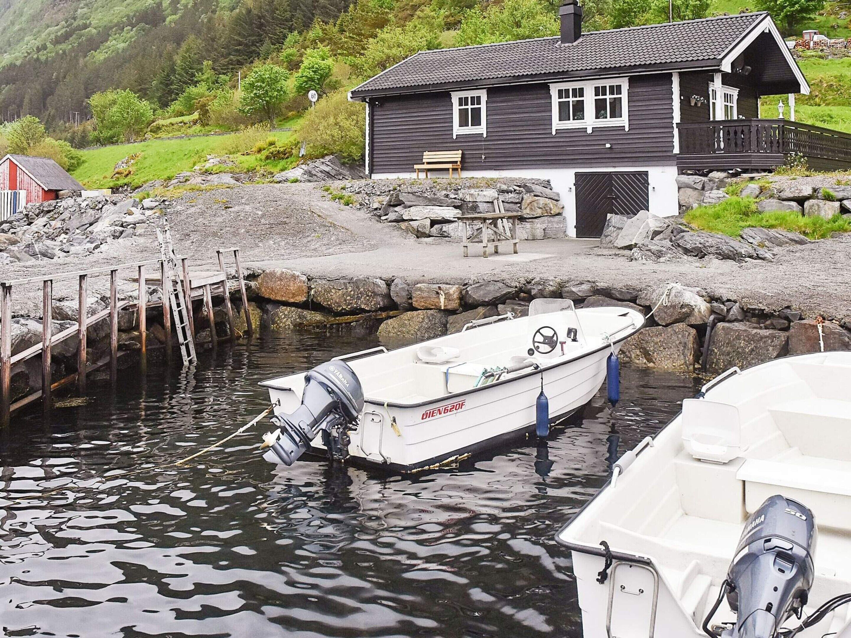 A boat docked at a pier with a house in the background.
