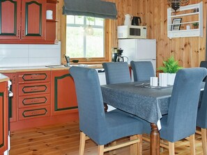 A wooden-paneled kitchen with a dining table, chairs, and a microwave. - Holiday Home in Selje (Stad)