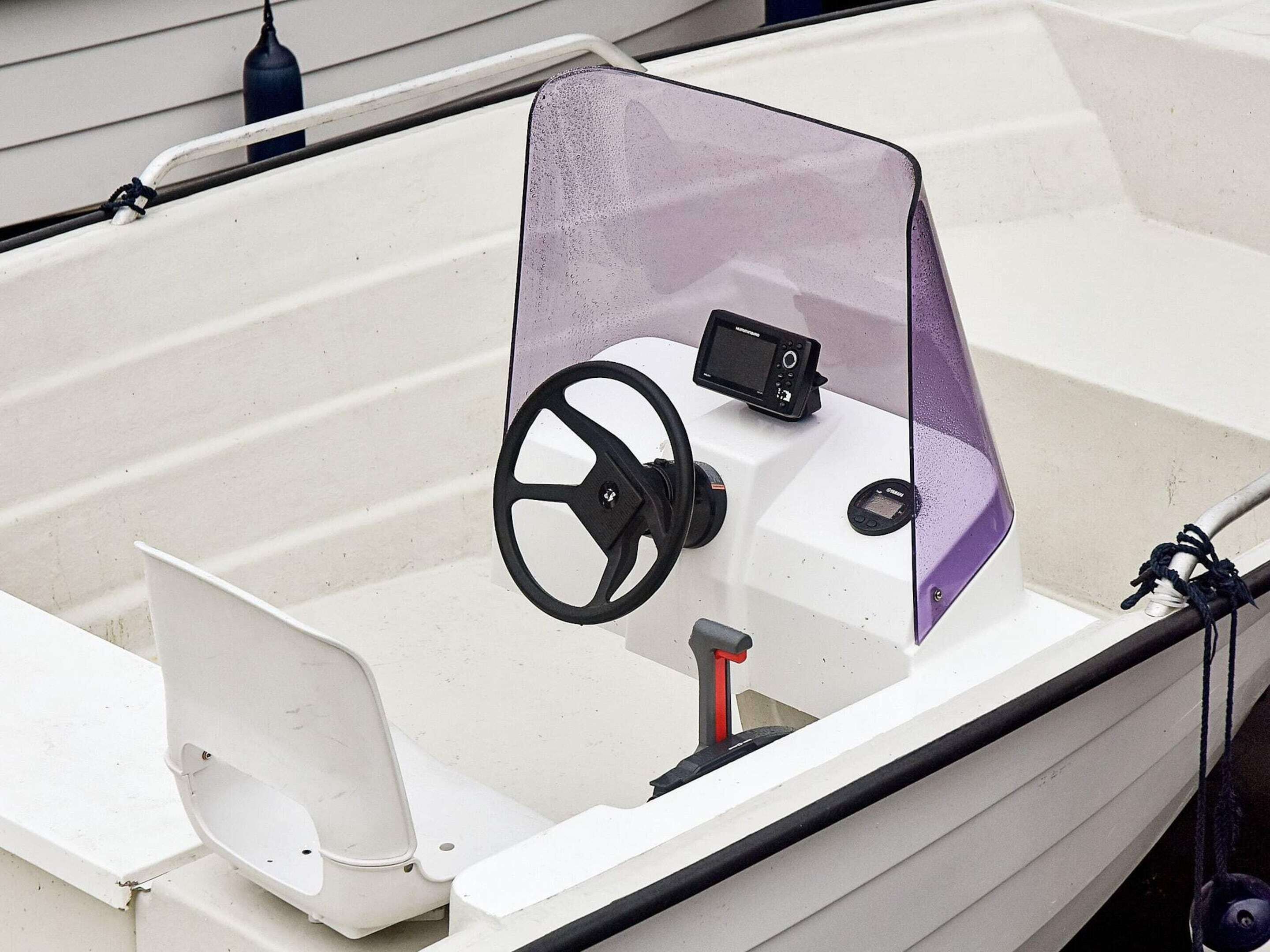 L'intérieur d'un bateau, avec un volant, un panneau de commande et un pare-brise.