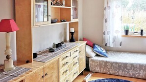 A cozy room with a wooden cabinet, a small bed, a window with curtains, and a lamp. - 5 Person Holiday Home in Digermulen (Vagan)