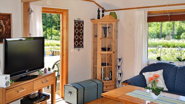A living room with a television, wooden furniture, a cabinet, and a view of the outdoors. - 5 Person Holiday Home in Digermulen (Vagan)
