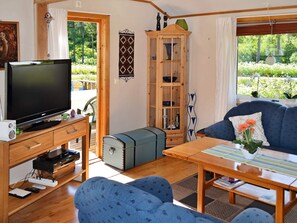 Un salon équipé d’un téléviseur, de meubles en bois, d’une armoire et offrant une vue sur l’extérieur.