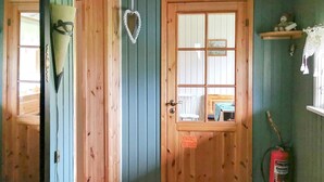 A wooden door with a heart-shaped decoration, a fire extinguisher, and a small shelf with a teddy bear. - 5 Person Holiday Home in Digermulen (Vagan)