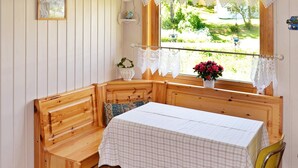 A wooden bench with a table, lace curtains, and a window with a view of greenery. - 5 Person Holiday Home in Digermulen (Vagan)