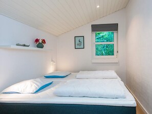 A bedroom with a bed, a window with a view of greenery, a wall-mounted shelf with decorative items, and a wall-mounted picture. - 5 Star Holiday Home in Juelsminde (Horsens)