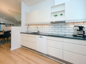 A modern kitchen with white cabinetry, a black countertop, and a coffee maker. - 5 Star Holiday Home in Juelsminde (Horsens)