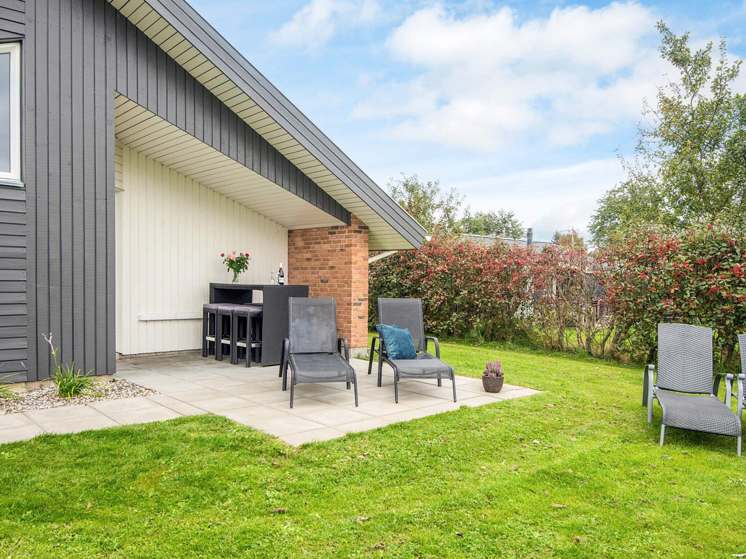 A modern outdoor patio with a built-in seating area, a brick wall, and a well-maintained lawn.
