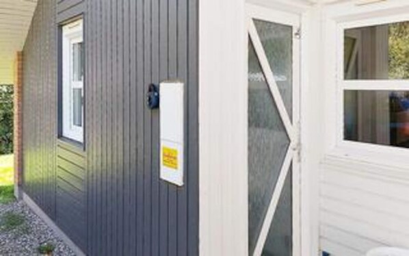 A small, single-story building with a grey exterior and a white door. - 5 Star Holiday Home in Juelsminde (Horsens)