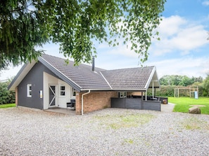 A two-story house with a covered patio area, a brick exterior, and a gravel driveway. - 5 Star Holiday Home in Juelsminde (Horsens)