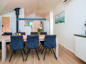 A modern dining area with a wooden table, blue upholstered chairs, and a vase of flowers. - 5 Star Holiday Home in Juelsminde (Horsens)