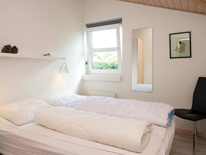 A bedroom with a bed, a chair, a window, a bedside lamp, and a mirror. - 5 Star Holiday Home in Juelsminde (Horsens)