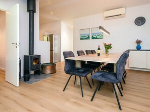 A modern kitchen with a built-in stove, a dining table with chairs, and a clock on the wall.