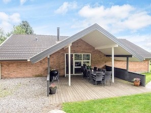 A covered patio area with a brick building, outdoor seating, and a gravel ground. - 5 Star Holiday Home in Juelsminde (Horsens)