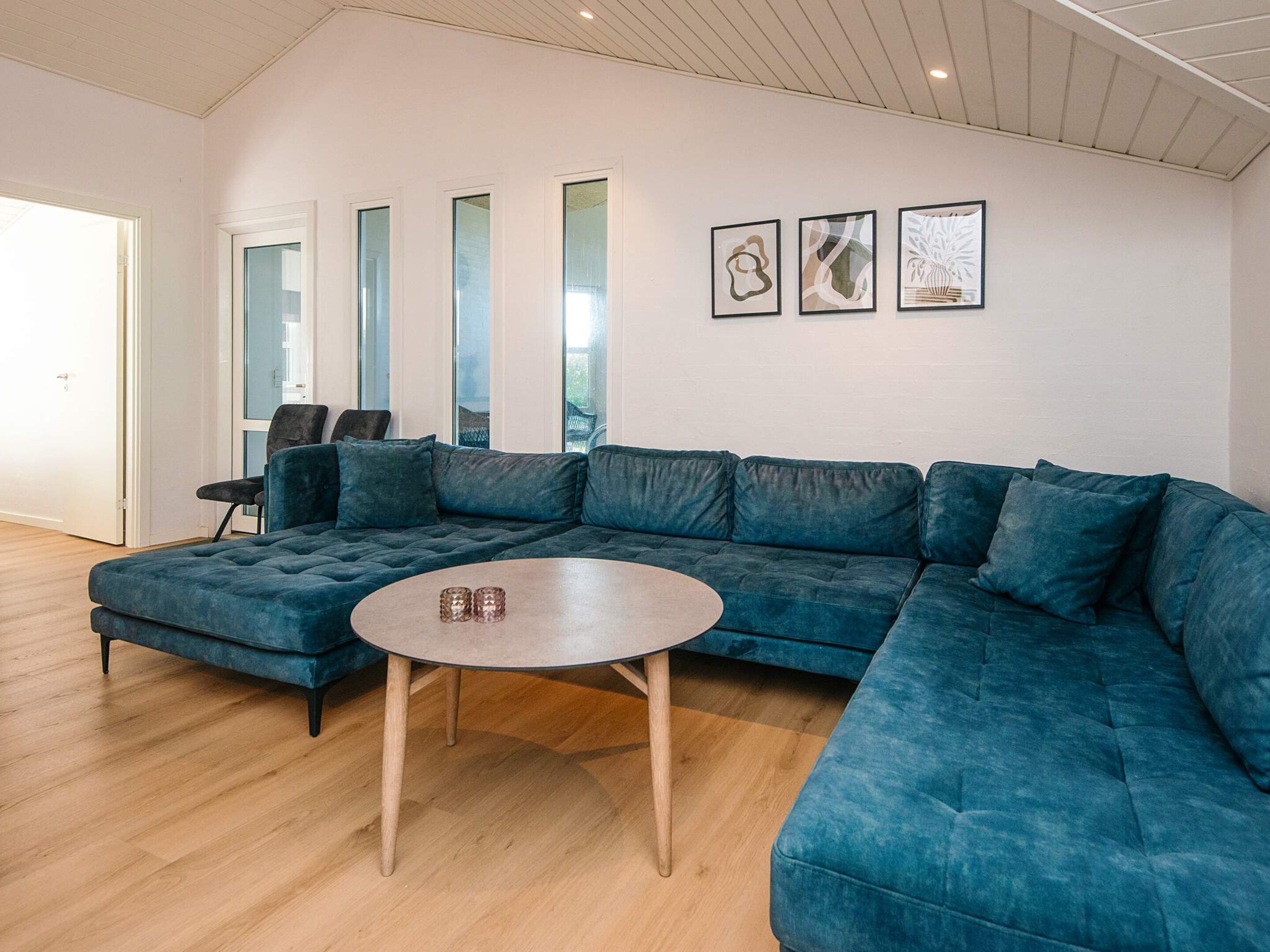 A modern living room with a large sectional sofa, a round coffee table, and a glass door leading to a balcony.