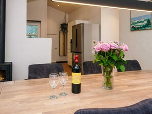 A dining area with a table set for two, a bottle of wine, and a vase of flowers. - 5 Star Holiday Home in Juelsminde (Horsens)