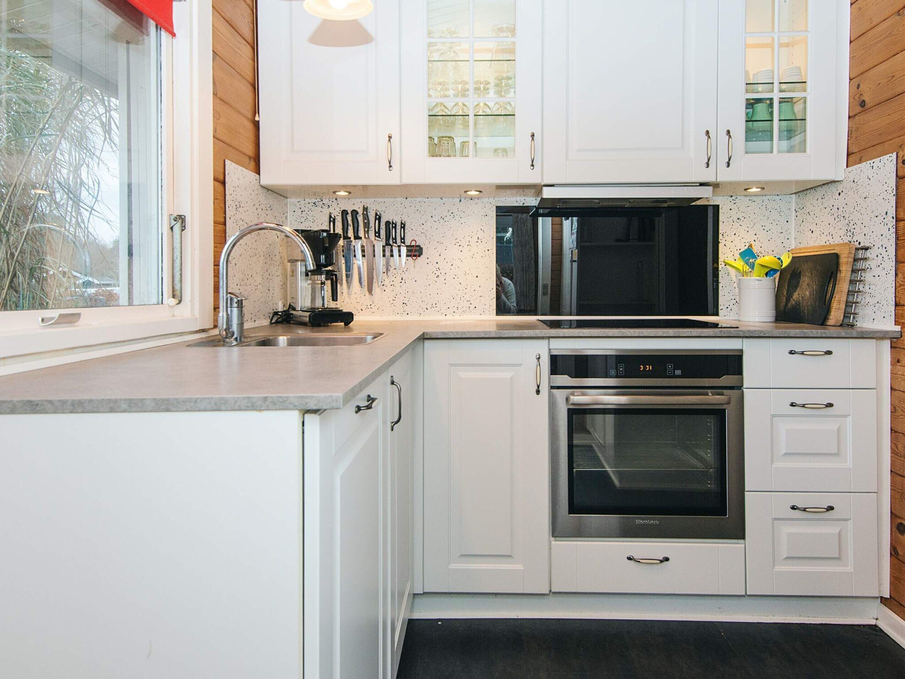 A modern kitchen with white cabinets, a stainless steel oven, and a microwave.