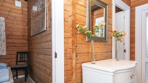 Een houten interieur met een witte linnenkast, een spiegel en een stoel.