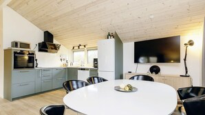 A modern kitchen with grey cabinets, a white dining table, and black chairs. - 6 Person Holiday Home in Vaeggerlose-by Traum (Vaeggerlose)