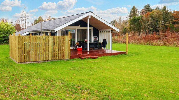 A single-story house with a covered patio area, a wooden fence, and a lawn. - 6 Person Holiday Home in Vaeggerlose-by Traum (Vaeggerlose)