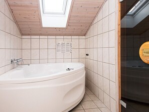 A modern bathroom with a freestanding bathtub, tiled walls, and a skylight. - Family-friendly Beach House - By Traum Ferienwohnungen (Borkop)