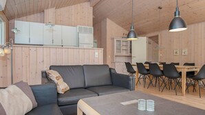Un salon moderne comprenant un canapé, une table basse et un coin repas avec des chaises et une table.