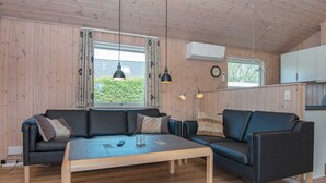 Un salon chaleureux avec un canapé, une table basse et un coin cuisine à l’arrière-plan.