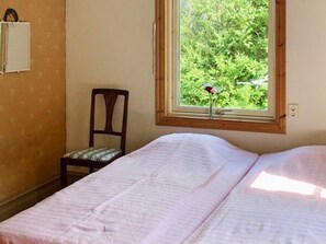 A bedroom with a bed, a chair, a window with a view of greenery, and a wall-mounted shelf. - 5 Person Holiday Home in Kungshamn (Kungshamn)