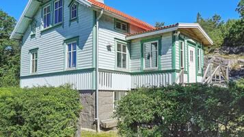 A two-story house with a red-tiled roof, white siding, and green trim.