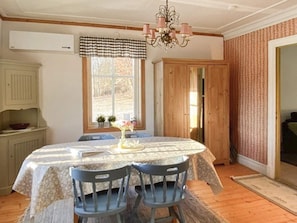A dining area with a table set for two, two chairs, a chandelier, a window with curtains, and wooden doors. - 5 Person Holiday Home in Kungshamn (Kungshamn)