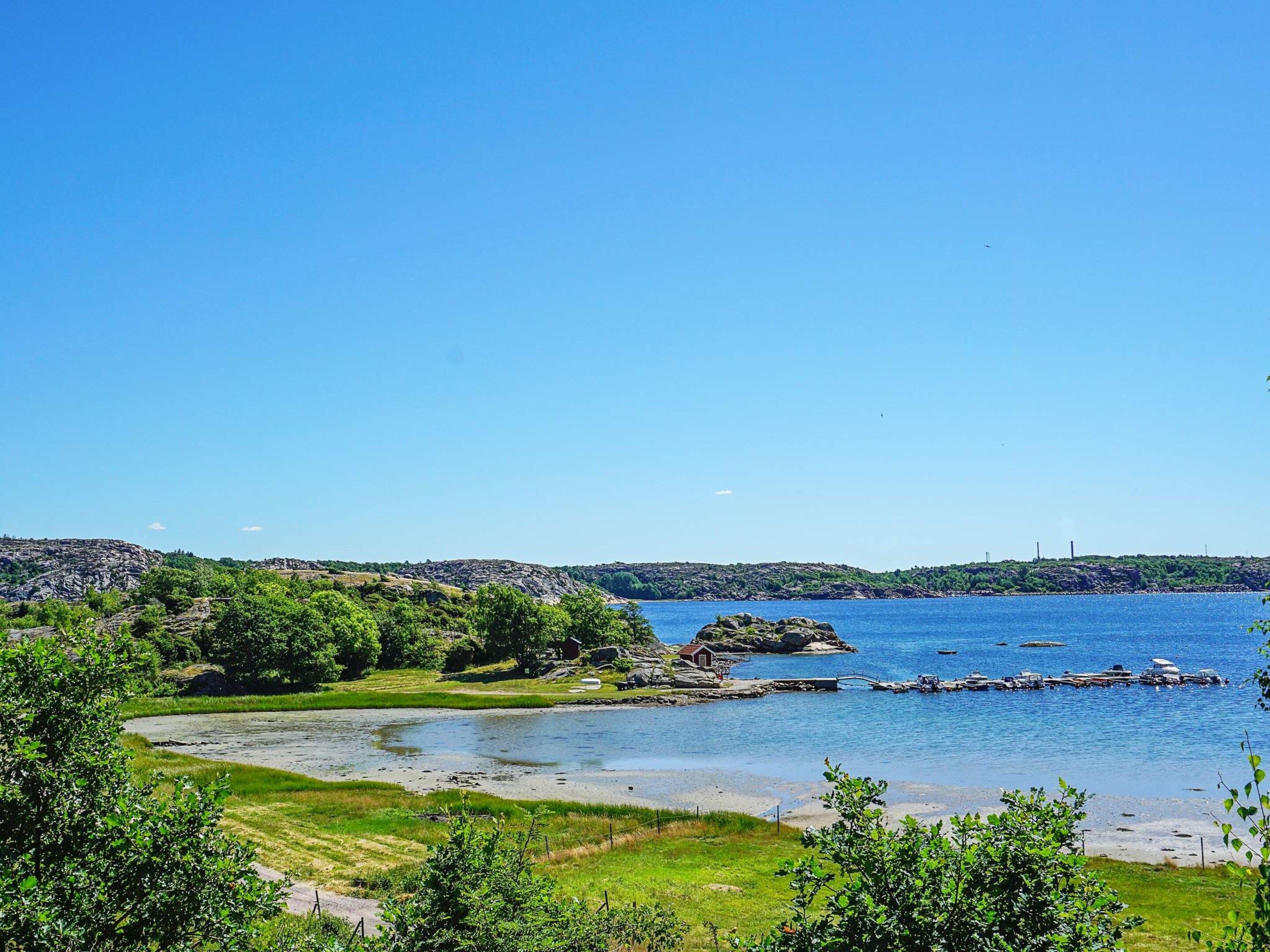 A coastal landscape with a clear sky, a river leading to the sea, and rocky terrain.