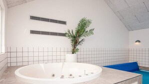 Et moderne badeværelse med et fritstående badekar, en potteplante og en blå badeværelsesmåtte.