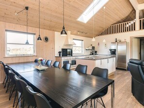 A modern kitchen with a central island, wooden ceiling, and pendant lighting.
