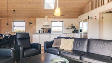 Et moderne interiør med spiseplads, sofa og køkken.