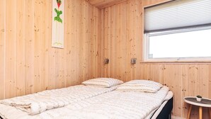 Una habitación con paneles de madera, una cama, una mesita y un ventanal.