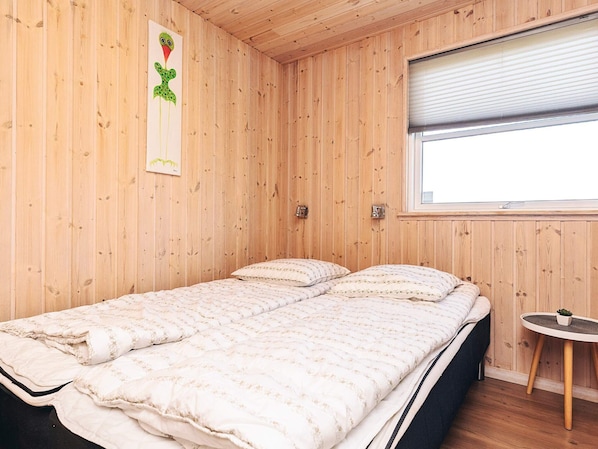 A wooden-paneled room with a bed, a small table, and a window. - 5 Star Holiday Home in Lokken (Lokken)