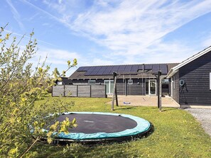 A house with a trampoline, a wooden fence, and solar panels on the roof. - 5 Star Holiday Home in Lokken (Lokken)
