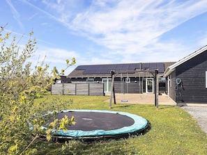 A house with a trampoline, a wooden fence, and solar panels on the roof. - 5 Star Holiday Home in Lokken (Lokken)