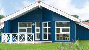 Een blauw huis met een witte veranda en een rood dak.